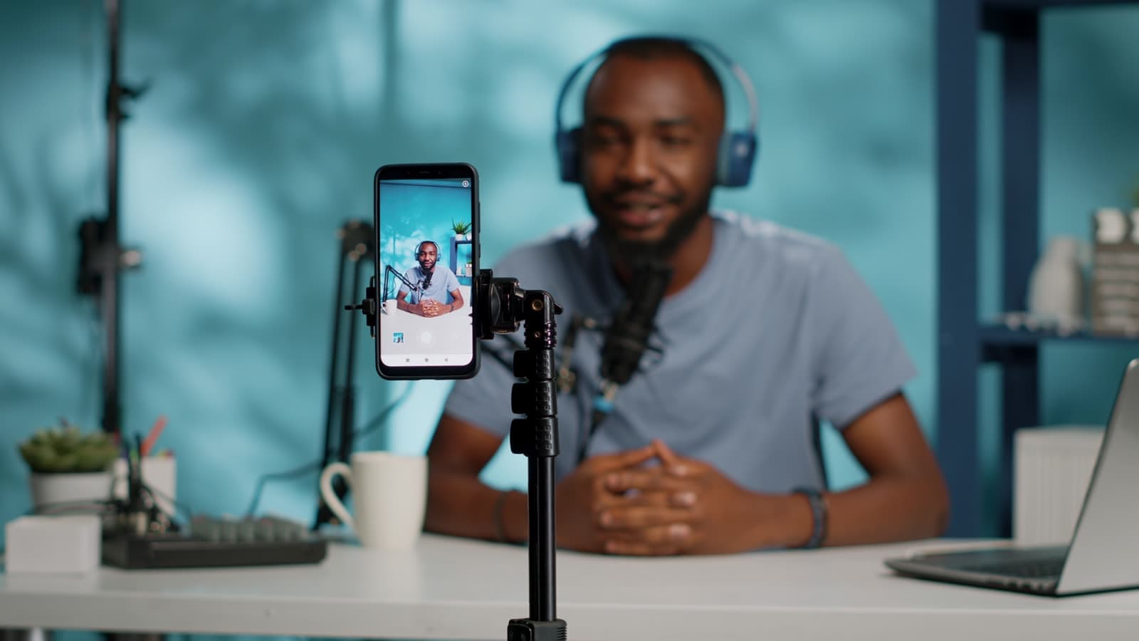 A man at his desk recording himself on a phone with a small microphone